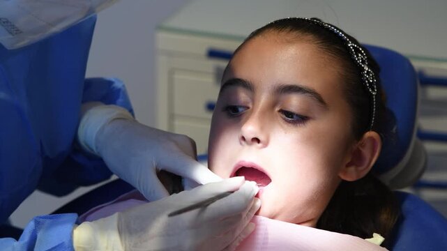 Young girl seating at dentist chair preparing for teeth cleaning. Slow motion