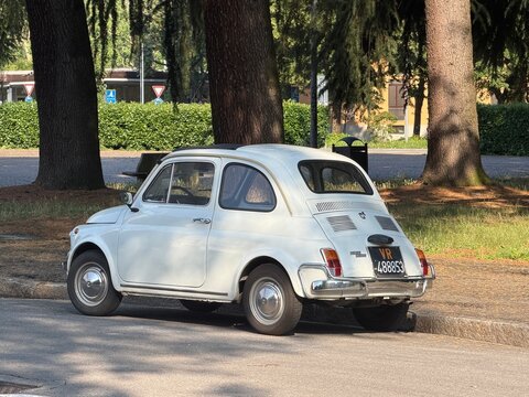 Retro White Automobile: A classic white hatchback parked in an outdoor setting, showcasing its vintage design and iconic silhouette against a backdrop of trees and greenery. Milan, Italy