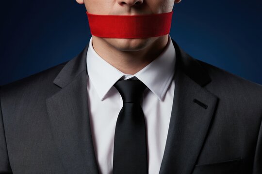 Man in suit wears red tape across mouth. Concept of silenced speech, censorship, and restricted expression. Represents oppression and lack of freedom.