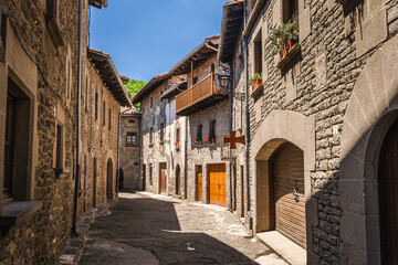 Fototapeta premium Narrow medieval street lined with traditional stone houses in Rupit village, Catalonia, Spain, featuring rustic architecture