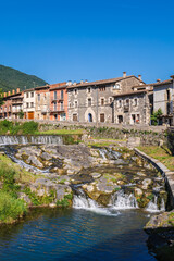 Fototapeta premium Traditional stone houses and cascading river in Catalan mountain village, scenic rural landscape with historic architecture