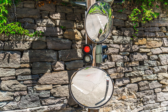 Traffic light and convex mirrors mounted on stone wall in medieval mountain village