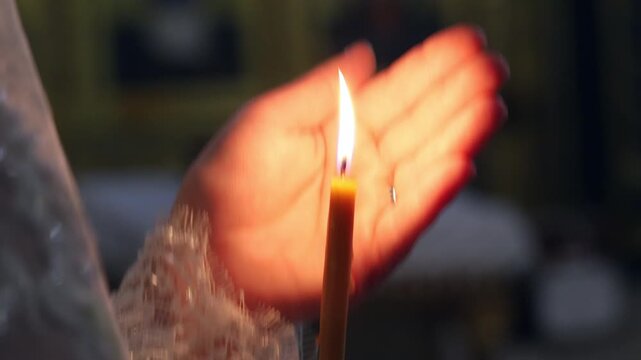 Selective focus on a woman hand with a lit candle in an orthodox church ritual