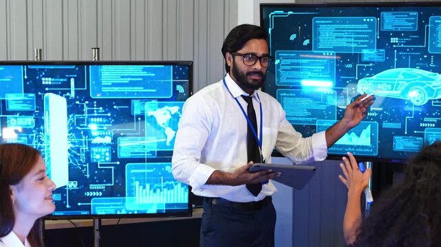 Indian IT expert holding tablet pointing pen at car blueprint screen interface during smart vehicle technology project development presentation to office team audience.