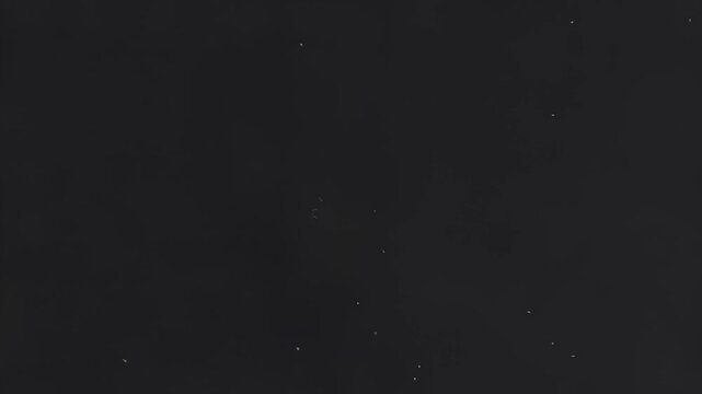 Small white particles floating and drifting slowly in a dark void creating a subtle motion video effect with soft lighting and organic movement captured in this high quality abstract animation