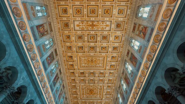 A stunning interior view of the Basilica of Saint Paul Outside the Walls in Rome, Italy, featuring rows of majestic marble columns and a magnificent gilded coffered ceiling.
