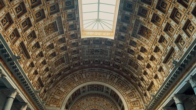 A stunning interior view of the Basilica of Saint Paul Outside the Walls in Rome, Italy, featuring rows of majestic marble columns and a magnificent gilded coffered ceiling.
