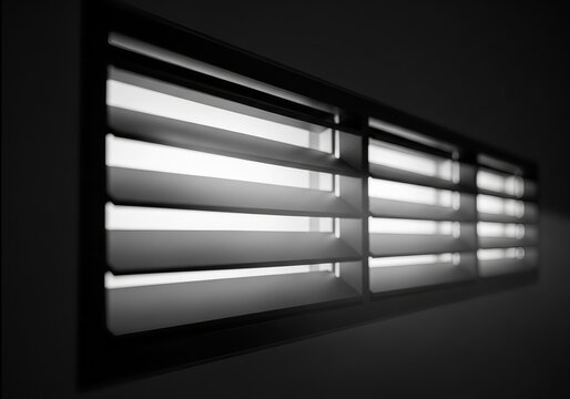 Perspective view of light streaming through a dark architectural window louver vent at night