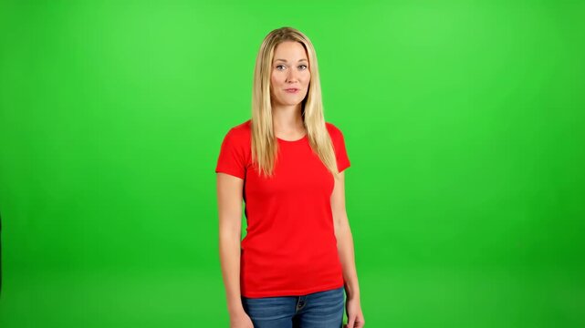 The blonde woman standing in front of the green screen, the woman in red in front of the green screen