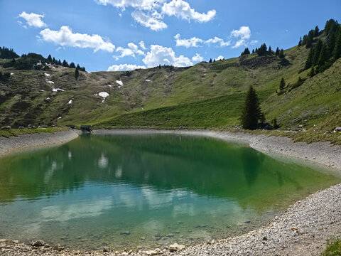 Austria, Charming mountain lake reflecting clouds blue skies and pristine alpine landscapes on Hahnenkamm