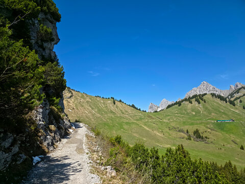 Austria, Inspiring hiking trail beneath towering mountain rocks across vibrant alpine meadows and scenic valleys