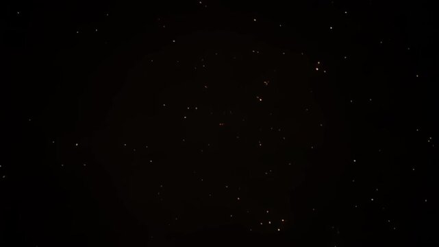 Golden light particles expanding in a dark void creating a mesmerizing animation sequence of glowing sparks drifting away from the bright center point in this high quality abstract digital motion foot