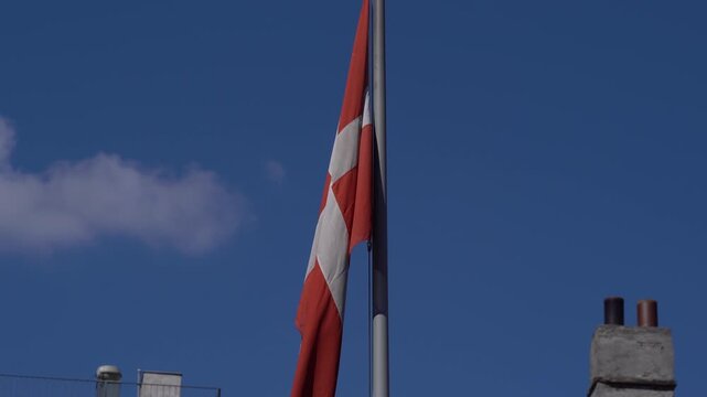 Danish Flag Dannebrog Waving on Flagpole Against Blue Sky in Copenhagen