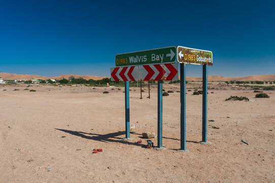Wide Scene of Remote desert road sign in Namib desert near Walvis Bay showing directions to Gobabeb and isolated dune landscape