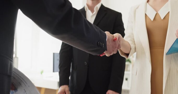 Handshake seals business partners agreement during meeting. Colleagues and team in office finalize contract terms with confidence trust and deal clarity. Symbol of partnership trust and success.