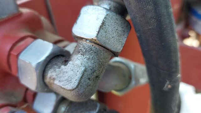 Close up of a worker pointing at a high pressure hydraulic hose connection fitting