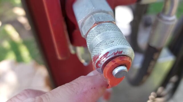 Close up of an industrial hydraulic quick coupler with a red protective cap