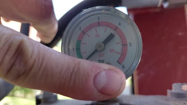 Worker checking an industrial pressure gauge manometer showing bar and psi