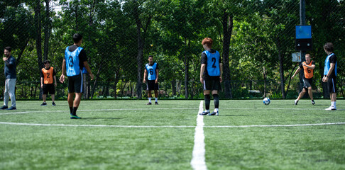 Obraz premium Soccer coach leading a practical training drill with players on an outdoor football field