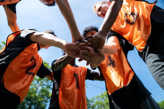 Soccer players stacking hands together in a team huddle before a match, demonstrating unity