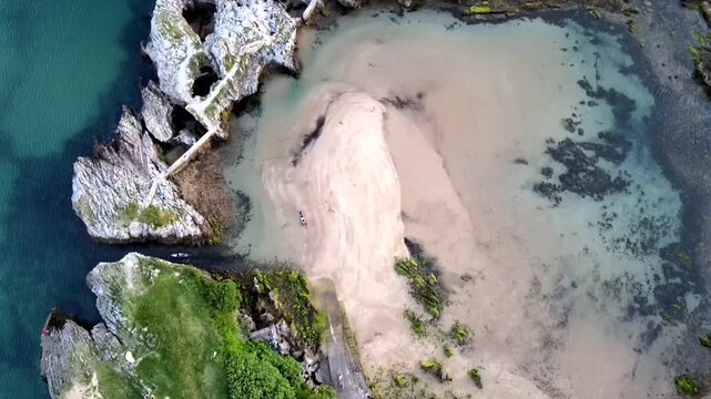 Aerial video of a canoe crossing the channel from the harbour to Las Arenillas beach in Islares, Castro Urdiales, Cantabria
