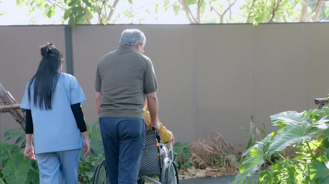 Female caregiver assisting senior man walking outdoor garden pushing wheelchair providing peaceful homecare nursing assistance supporting health recovery wellness retirement sunny afternoon
