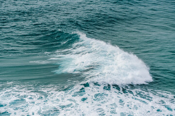Naklejka premium Ocean wave breaks in a smooth curve with white foam