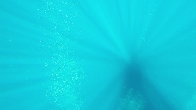 Sunbeams and air bubbles in the water. Underwater sun rays and bubbles from divers. Scuba diving in the azure lagoon with sun and air. Blue ocean, scuba diving travel footage.
