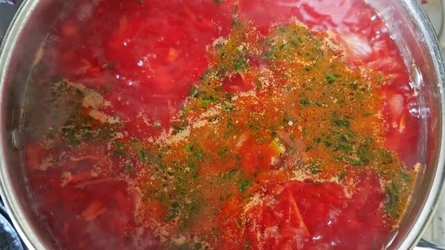 Boiling borscht soup in a pot viewed from above with rising steam, close up cooking process, traditional homemade cuisine, comfort food preparation