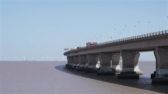 Sea Bridge Trucks Driving Past Offshore Wind Farm Fixed Camera Coastal Transport