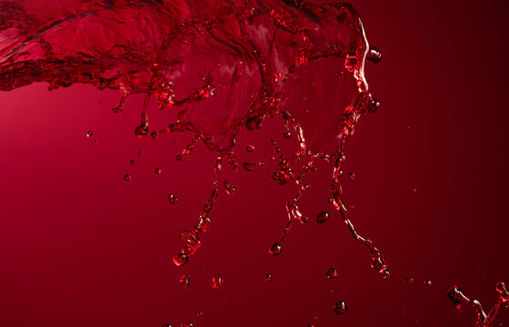 Glass and red wine splash on a dark red background.