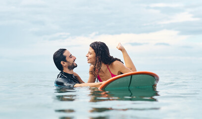 Obraz premium Portrait of a young couple surfing at the beach, holding surfboards, having fun together ocean waves, healthy life holidays adventure concept