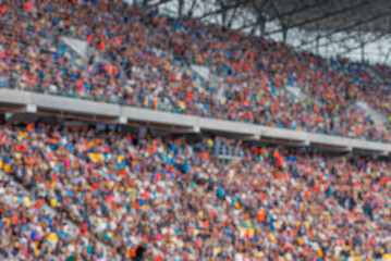 A blurred background of a large crowd of spectators sitting in the stands of a sports stadium during an event. © Denis Rozhnovsky
