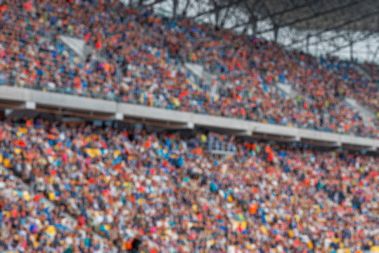 A blurred background of a large crowd of spectators sitting in the stands of a sports stadium during an event.