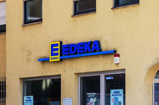 Augsburg, Germany &mdash; May 31 2026: An Edeka supermarket corporate logo sign mounted on a textured beige building wall above the store entrance