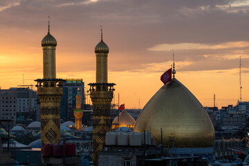 Naklejka premium Karbala, Iraq - December 28, 2025: Golden dome and illuminated minarets of the Imam Hussain Shrine glowing at dusk in Karbala, Iraq