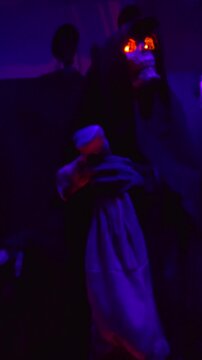 An animatronic Grim Reaper holding a bag whose eyes glow in the dark at Halloween.