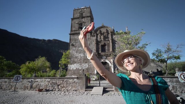 Senior woman smiles and takes selfies at the San Javier Mission in Baja California Sur at sunrise, celebrating her adventure in Loreto