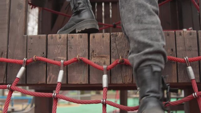 Individual crosses colorful bridge confidently. Figure carefully treads red bridge with textured soles. An individual approaches wooden and metal bridge with determined steps and winter gear