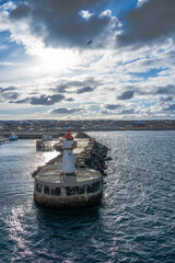 Obraz premium Lighthouse of norwegian town Vardo with blue sea and clouds in the background