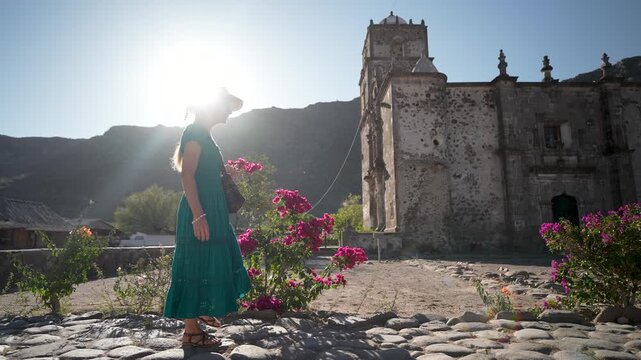 Mature woman walks through a garden at sunrise at San Javier Mission, feeling happy and excited while exploring the area