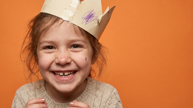 Smiling Young Girl Wearing Handmade Paper Crown in Studio