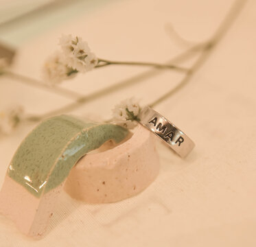 Silver ring engraved with Amar displayed with flowers and ceramic decor