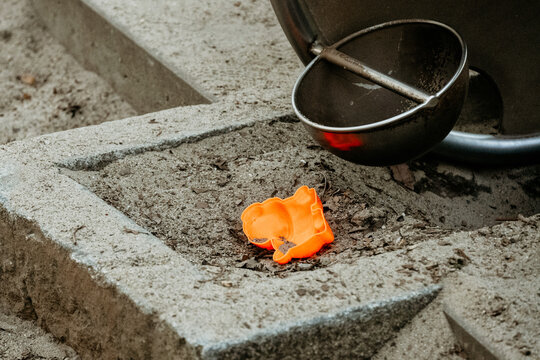 Orange plastic toy and metal scoop in sandbox at playground