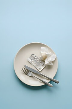 Empty blister pack and used napkin on plate with cutlery, light blue background, copy space, generative ai.