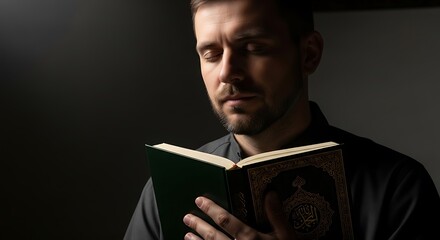 A man with a beard, dressed in dark clothing, is deeply engrossed in reading a book, his eyes closed in contemplation.
