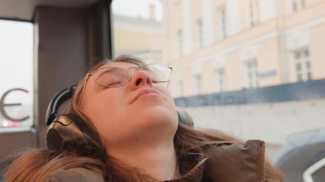 White woman wearing glasses and headphones dozing in bus seat, eyes closed in gentle nap frames alternate between tired student, weary traveler, podcast listener drifting to sleep, and commuter