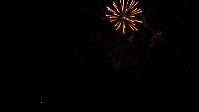 Fireworks bursts illuminate darkness with mesmerizing brilliance on holiday. Fireworks explosions paint temporary masterpiece in black sky. Amazing fireworks glowing trails in evening sky