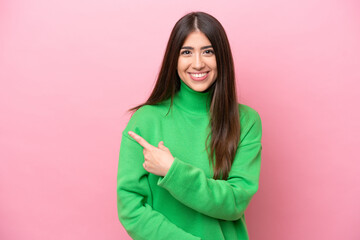 Fototapeta premium Young caucasian woman isolated on pink background pointing to the side to present a product