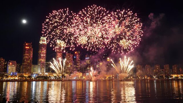 Fireworks exploding over a city skyline at night with a body of water